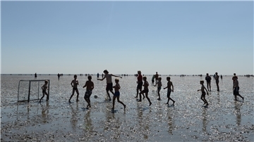 Kinder spielen im Watt Fußball. Im Ferienpass der Gemeinde Wurster Nordseeküste wird Wattfußball angeboten.