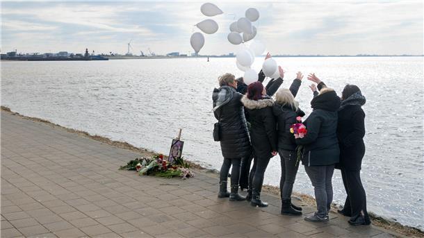 Frauen stehen am Deich und lassen Luftballons aufsteigen. 