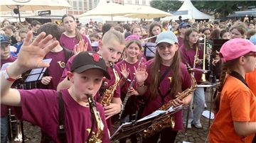 Viele Kinder mit Blasinstrumenten auf einem öffentlichen Platz.