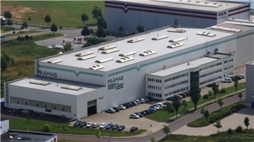 Luftaufnahme des Firmengebäudes der ehemaligen GMW PRÄMAB GmbH in Burg bei Magdeburg. Zu sehen sind die große Produktionshalle mit dem Schriftzug „PRÄMAB“ und ein angrenzendes Verwaltungsgebäude, umgeben von Parkplätzen und Grünflächen.