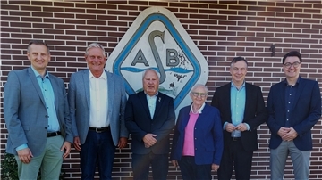 Sechs Personen stehen in festlicher Kleidung vor einer Backsteinwand mit dem Logo einer Anglervereinigung mit den Buchstaben "ASB". Es handelt sich um Vertreter des Verbands und Ehrengäste bei einer Jubiläumsfeier.