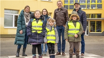 Gruppenfoto mit vier Erwachsenen und drei Kindern (die gelbe Warnwesten tragen) vor einer Schule. Projekt „Schulwegenetz“: Start an der Friedrich-Ebert-Schule zur Förderung sicherer und eigenständiger Schulwege für Schüler.