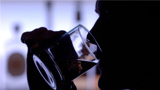 Ein Mann trinkt ein Glas Whiskey an einer Bar