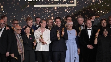 Zusammen mit Kulturstaatsministerin Claudia Roth (im blau-weiß gestreiften Kleid) stehen die Preisträger des Deutschen Filmpreises auf der Bühne.