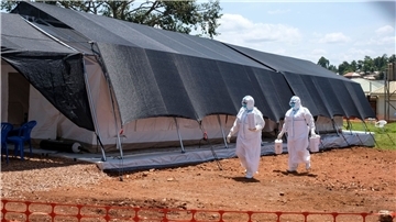 Zwei Ärzte in Schutzanzügen gehen zum Ebola-Isolationsbereich des Mubende Regional Referral Hospital. Im ostafrikanischen Uganda ist die Zahl neuer Infektionen mit dem tödlichen Ebola-Virus über das Wochenende rasant angestiegen.