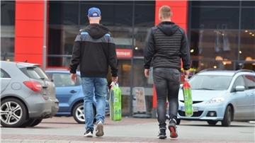 Zwei junge Männer tragen Toilettenpapier über den Parkplatz eines Zevener Supermarktes. In diesen Zeiten kein selbstverständliches Bild.