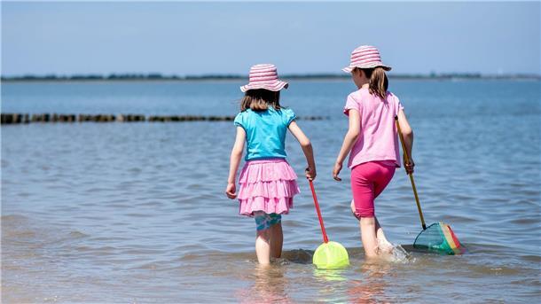 Nordsee erwartet viele Urlauber: Aber noch freie Betten Zwei Mädchen spielen bei sonnigem Wetter mit ihren Keschern im flachen Wasser der Nordsee am Strand.