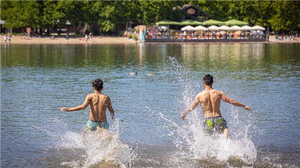 Lecker baden Zwei Männer rennen in einen Badesee.