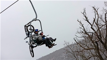 Zwei Männer sitzen mit ihren Mountainbikes in einem Sessellift.