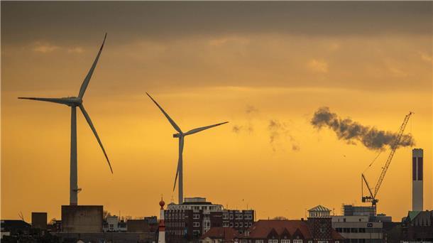 Zwei Windräder zeichnen sich vor dem morgendlichen Himmel in Bremerhaven ab.