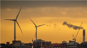 Zwei Windräder zeichnen sich vor dem morgendlichen Himmel in Bremerhaven ab.