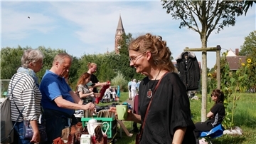 Menschen durchstöbern die Auslage auf einem Flohmarkt bei Sonnenschein